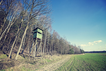 Vintage cross processed photo of hunting pulpit at the edge of a forest in spring, Poland.