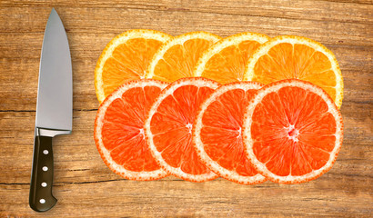 orange, grapefruit and knife on cutting board isolated on white
