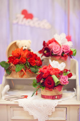Bouquets roses in a baskets on an old wooden dresser