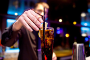 The bartender decorates  slice of lemon glass of fizzy drink