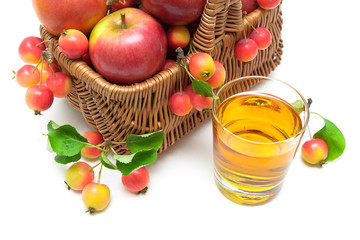 apples in a basket and a glass of apple juice on a white backgro