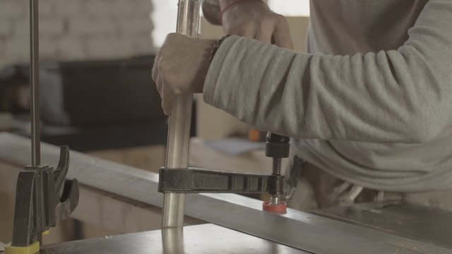 Professional carpenter fix metal balk on wooden board. Making furniture. Manufacturer. 
