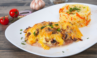 Meat under cheese and mushrooms with rice