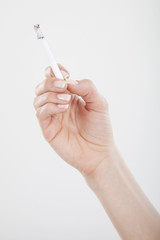 The woman hand is holding cigarette on white background. Focus on fingers