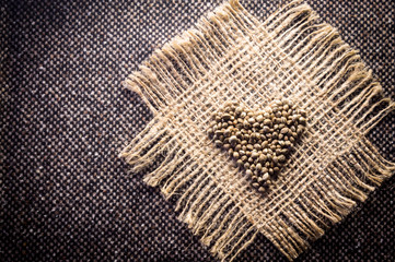 Hemp (cannabis) seeds heart on hemp fabric background