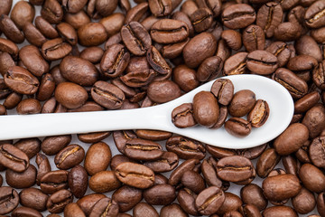 Coffee beans and small, white teaspoon 