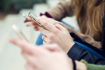 Obraz premium Three young women using a mobile phone in the street.
