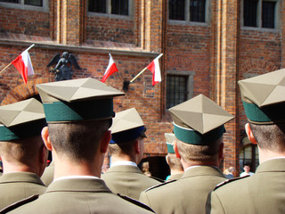 Obchody majowe z okazji rocznicy uchwalenia Konstytucji 3 Maja. Żołnierze wojska polskiego stoją na toruńskim rynku, a w tle polskie, biało czerwone flagi.