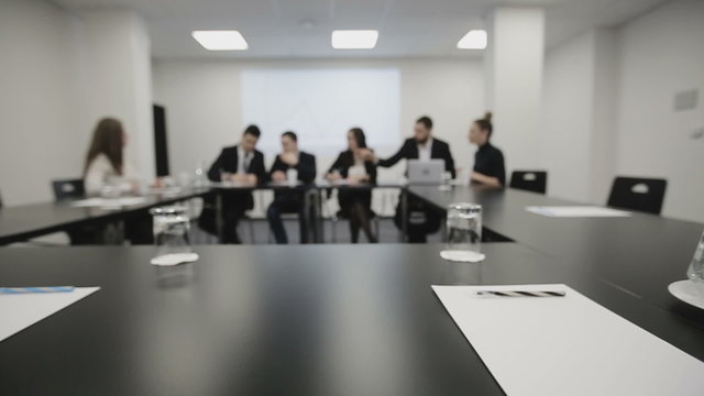 Business team at a meeting: Group of business people discussing, documents and ideas. Defocused footage, slider camera movement.