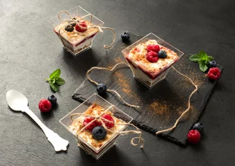 Fotobehang glasdessert met yoghurtroom en rood fruit op leisteen © TTLmedia