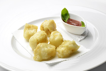 Fried pieces of codfish with tomato sauce
