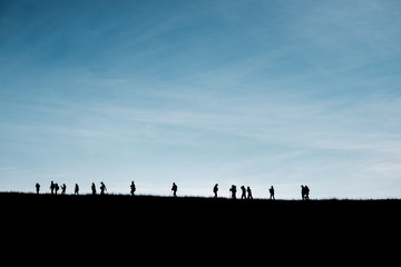 Silhouettes of travelers on the hill with blue sky