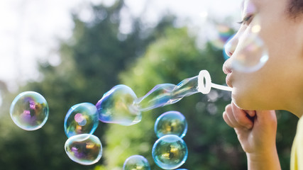 Close shot of little girl blowing bubbles outside