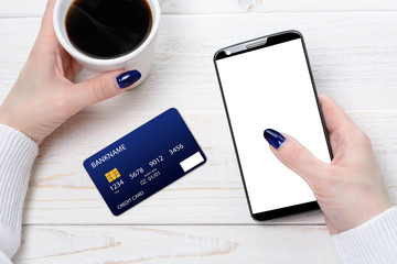 Woman sitting at table and pays the purchase through smartphone