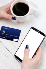 Woman sitting at table and pays the purchase through smartphone