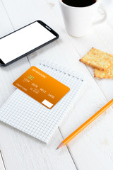 Smartphone, notebook, pencil and credit card on a white table