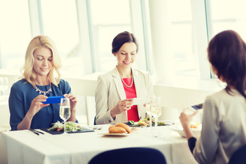 women with smartphones taking picture of food