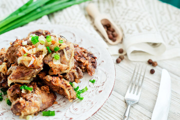 Fried chicken liver with green onion and spices on a wooden background