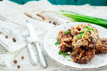 Fried chicken liver with green onion and spices on a wooden background