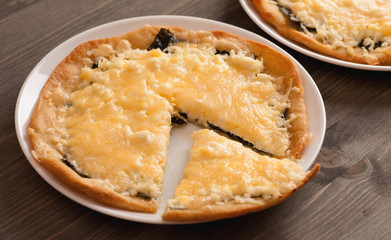 Homemade pie with cheese in white plate on wooden table