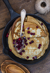 thin pancakes with cranberries in the pan