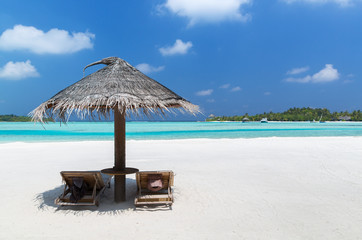 palapa and sunbeds by sea on maldives beach