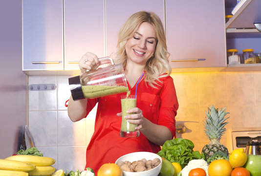Happy young woman pouring freshly made smoothie in the glass