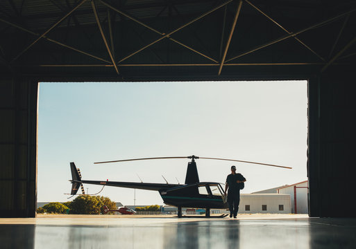  Pilot arriving at the airport with a helicopter in hangar
