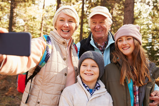 Senior woman taking outdoor selfie with grandkids and spouse