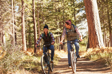 Fototapeta na wymiar Couple mountain biking through forest, close up