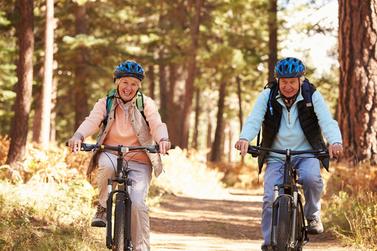 Senior couple cycling on forest trail, California
