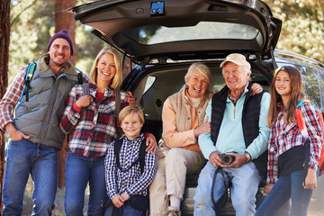 Multi generation family standing by a car before forest hike