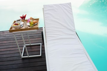 Tray with breakfast in side table and sun lounger 