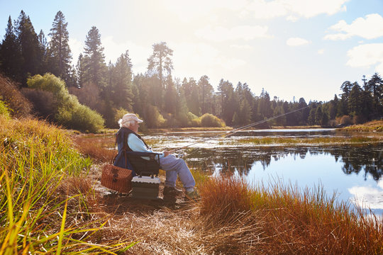 Senior man sits fishing, Bluff Lake, California