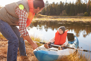 Father preparing launch for son in kayak on lakeside
