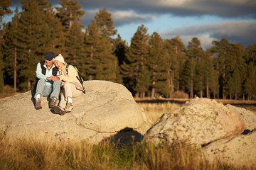 Senior couple sit on a rock near a forest, California, USA