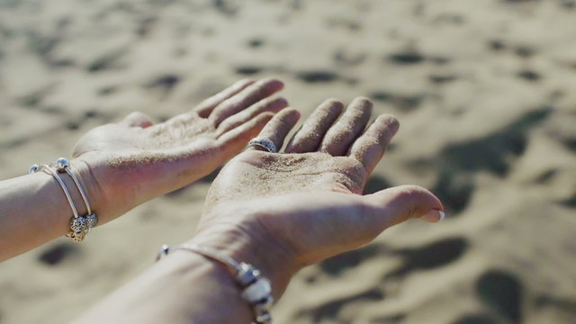 The woman rotates their hands with sand