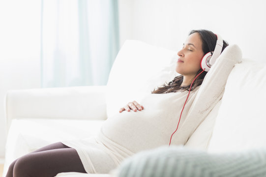 Pregnant Hispanic woman listening to headphones