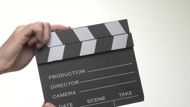 Hands using a movie clapper in front of a white background.