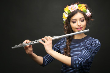 Beautiful young woman with flute on black background