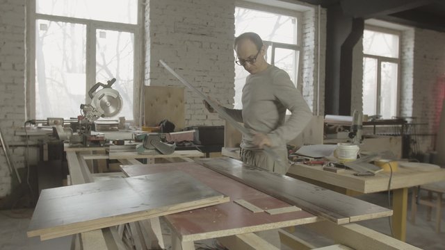Carpenter measure wooden board by metal balk on table. Process of making furniture. Manufacturer. 