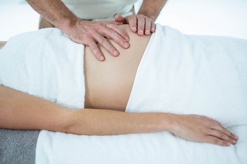 Fototapeta na wymiar Pregnant woman receiving a stomach massage from masseur