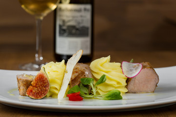 baked ham with mashed potatoes, figs, lettuce, peppers, radishes on a white plate