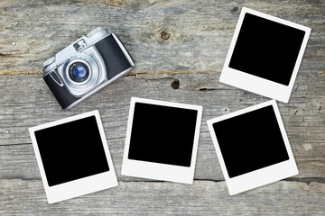 Old analog camera with blank photo frames, on wooden surface