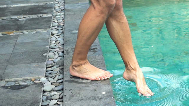 Male feet playing with water in swimming pool, super slow motion 240fps
