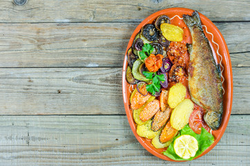 Trout with vegetables on a clay plate