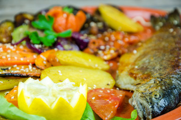 Trout with vegetables on a clay plate