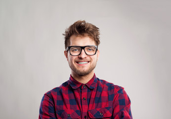 Obraz premium Man in checked shirt and eyeglasses against gray background.