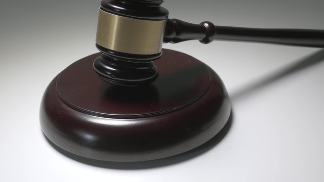 Dolly shot of a wooden judge gavel and soundboard isolated on white background.