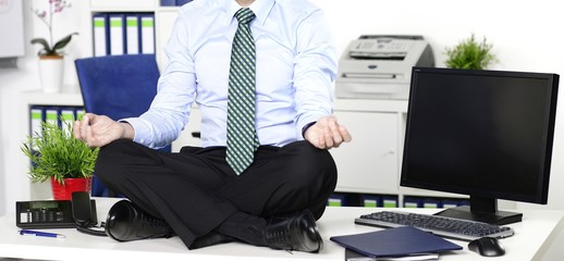 Mann im Anzug macht Yoga am Arbeitsplatz im Büro